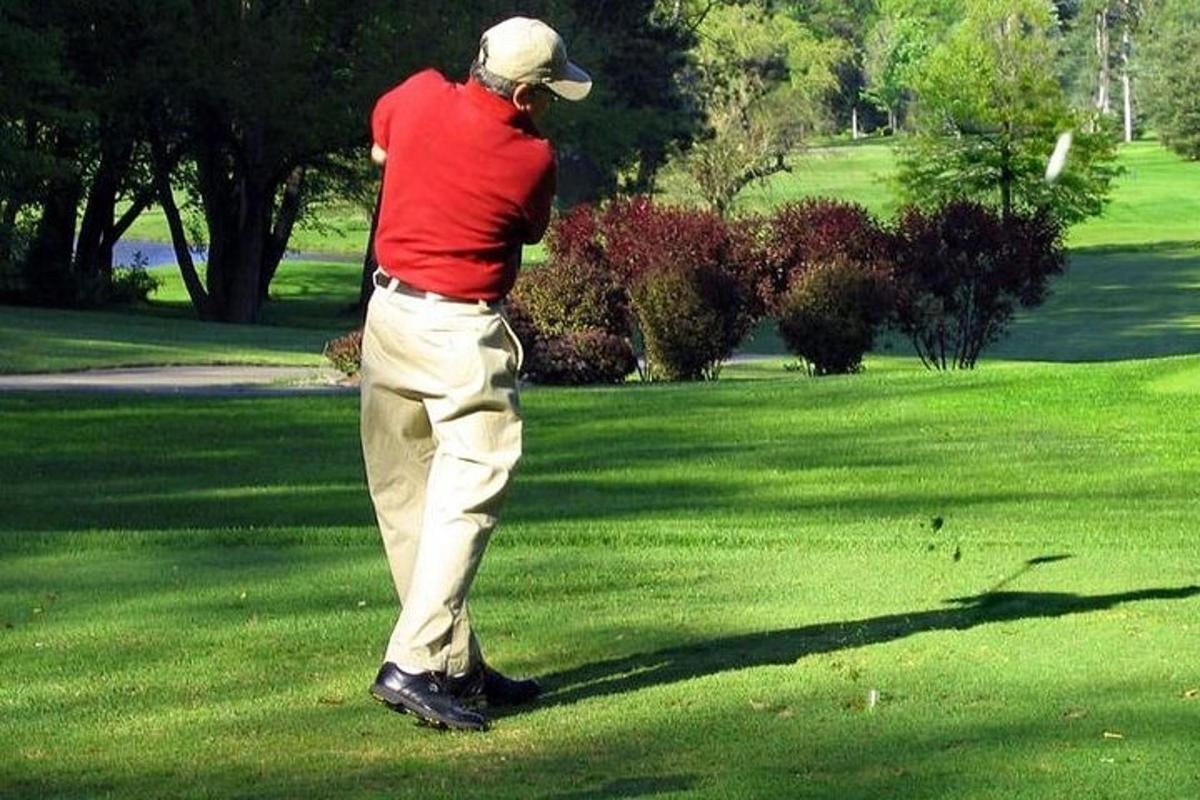 moški v rdeči majici igra golf
