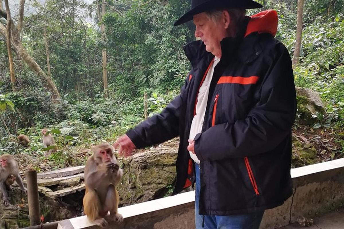 a man is petting a monkey on a fence