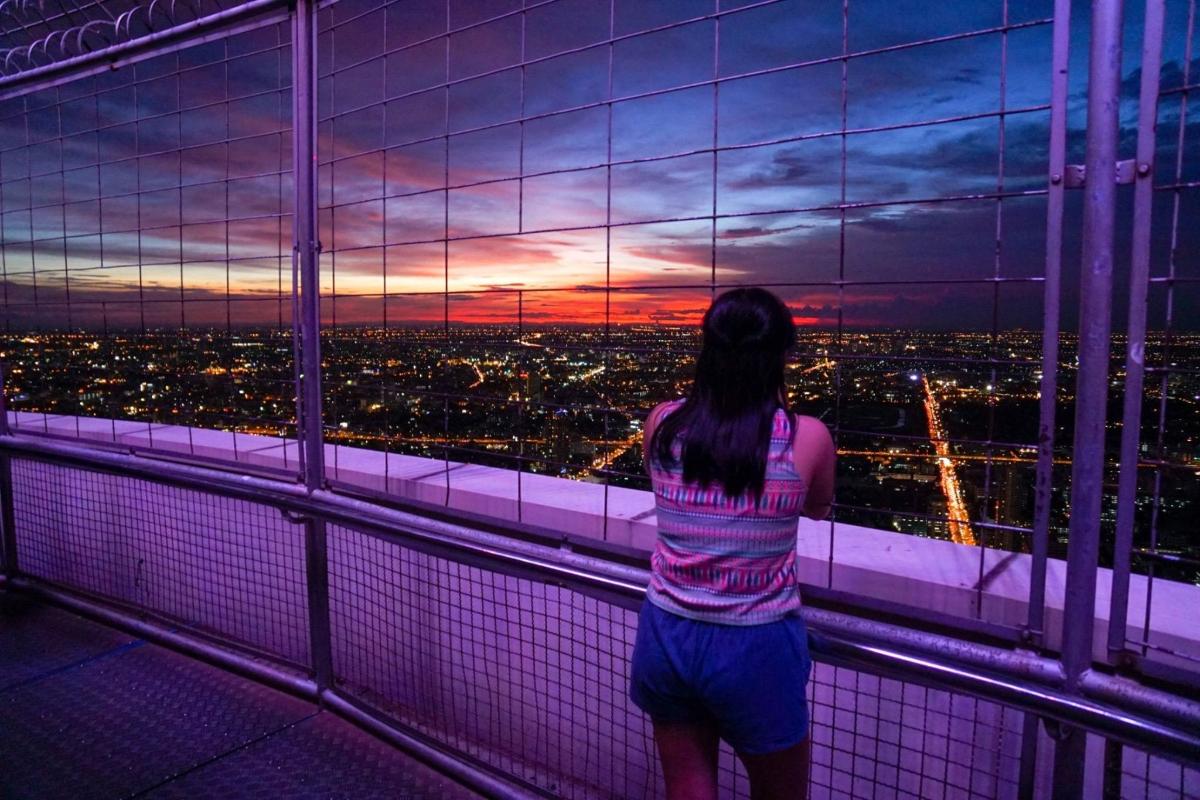 a woman looking out of a window at a sunset