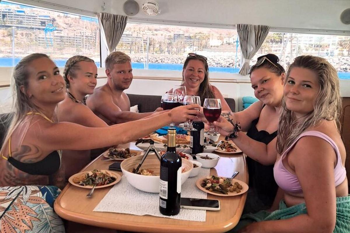 en gruppe mennesker sidder ved et bord med vinglas