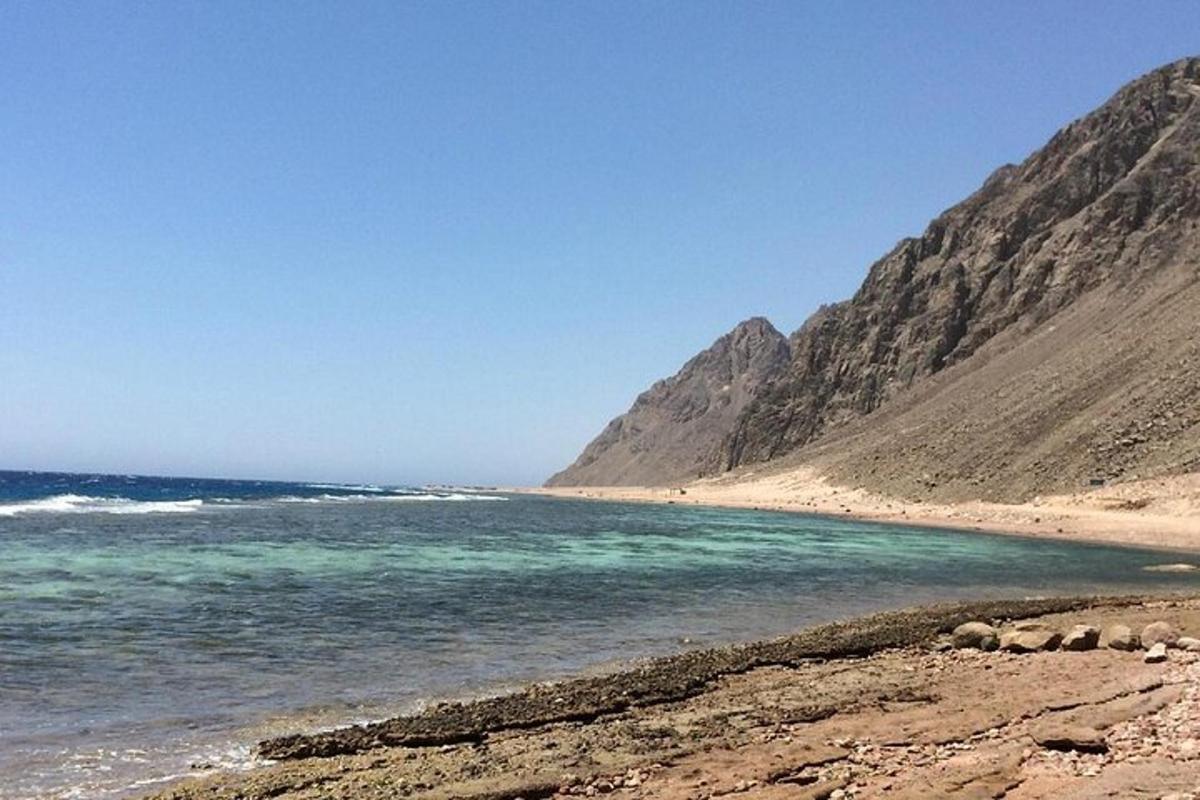 pantai dengan latar belakang lautan dan gunung