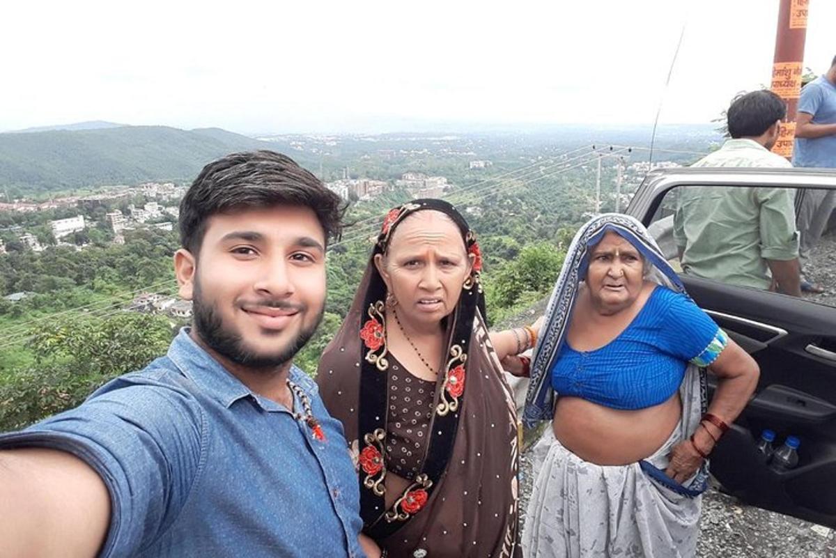 Un hombre y dos mujeres de pie en la cima de una montaña