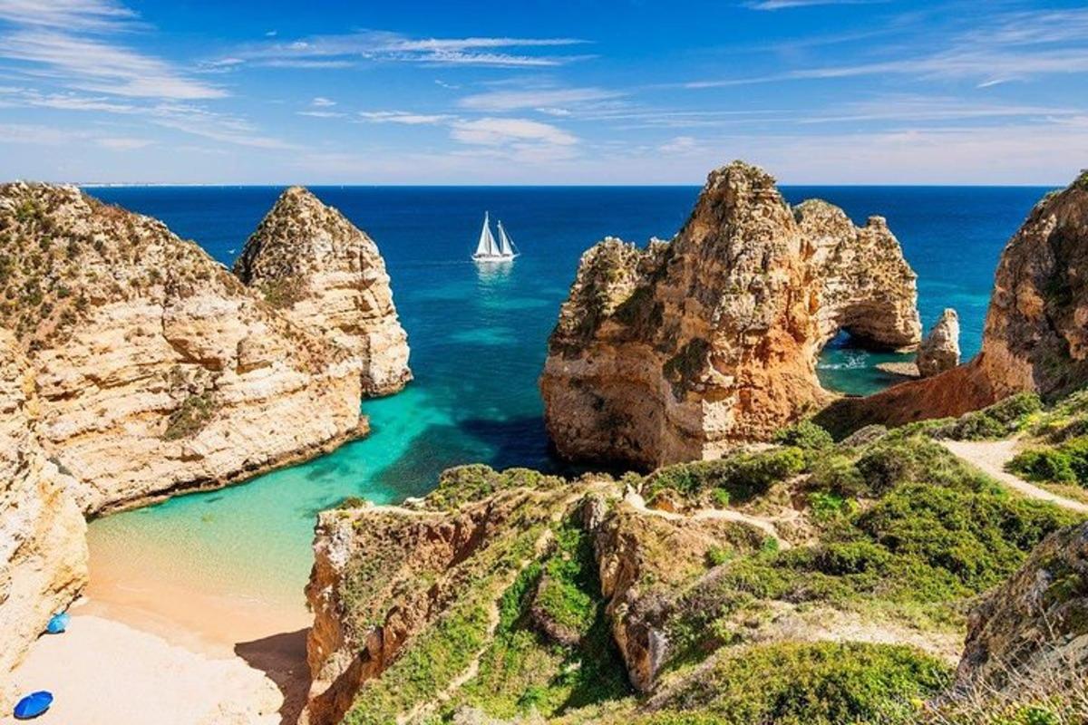 a sail boat in the ocean between rocks