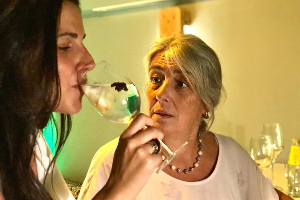 an older woman drinking from a wine glass