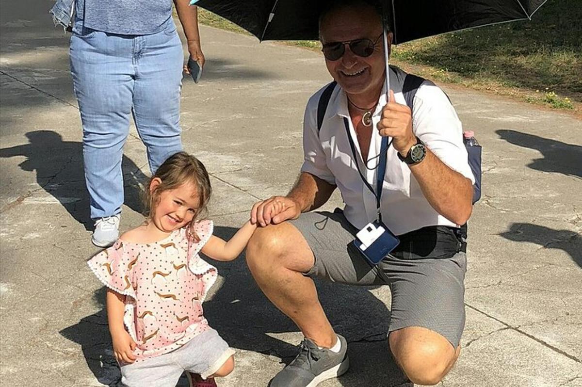 un uomo che tiene in braccio una bambina con un ombrello