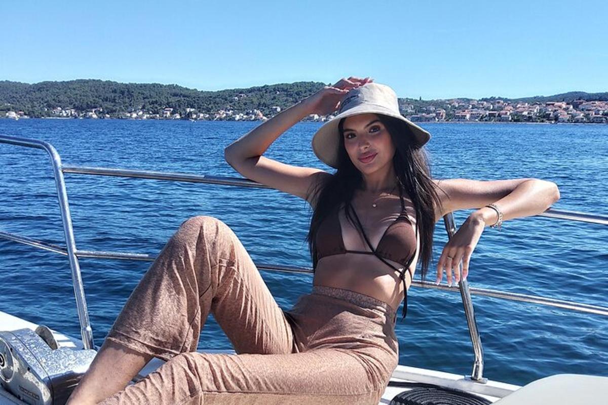 a woman in a bikini and hat sitting on a boat