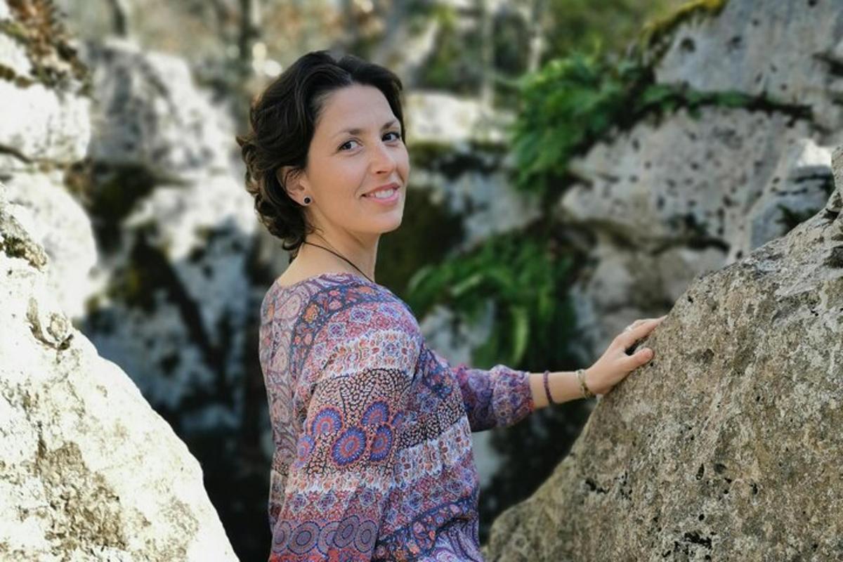 a woman is standing next to a rock