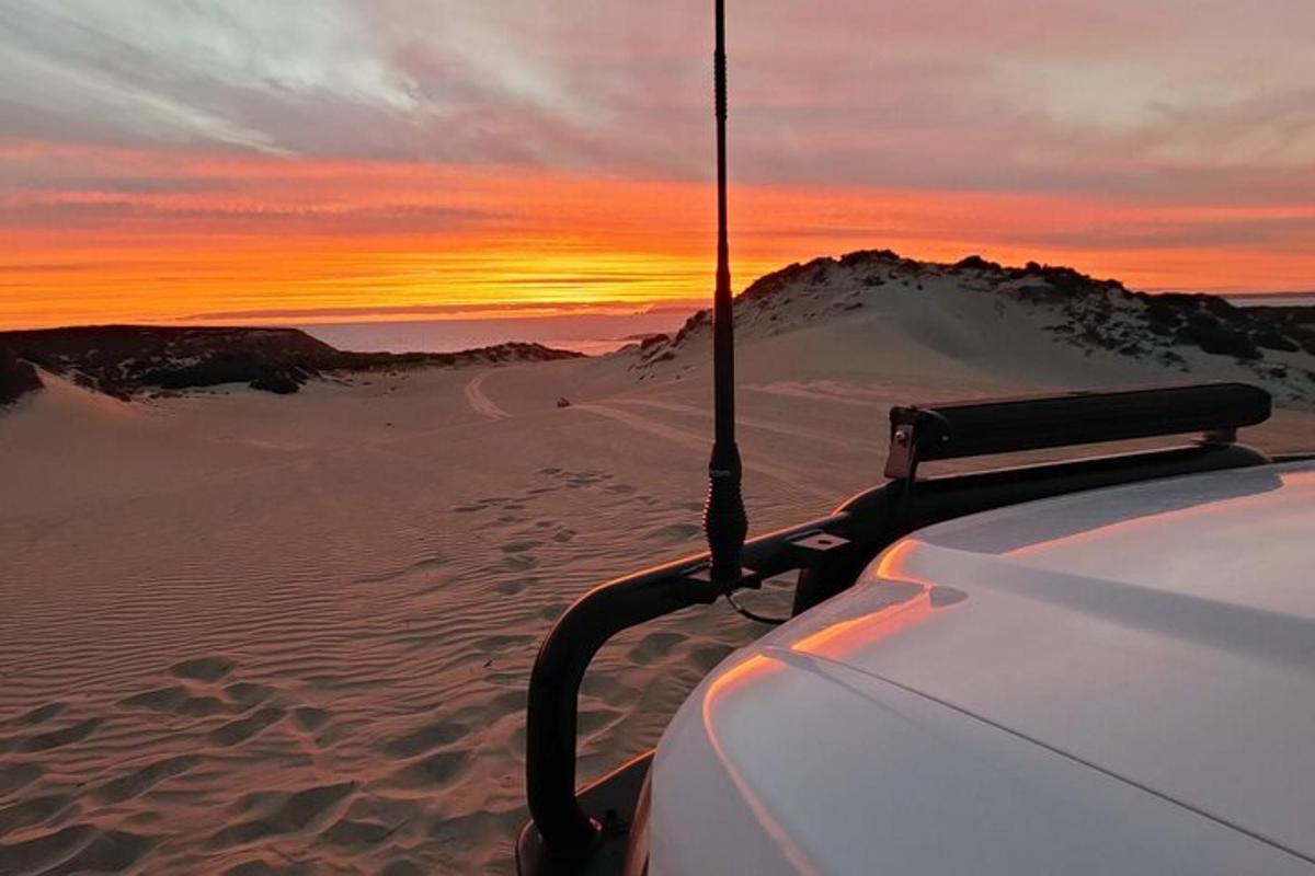 a car in the desert with a sunset in the background