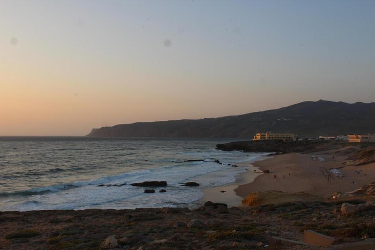 uma praia com o oceano e as montanhas ao fundo