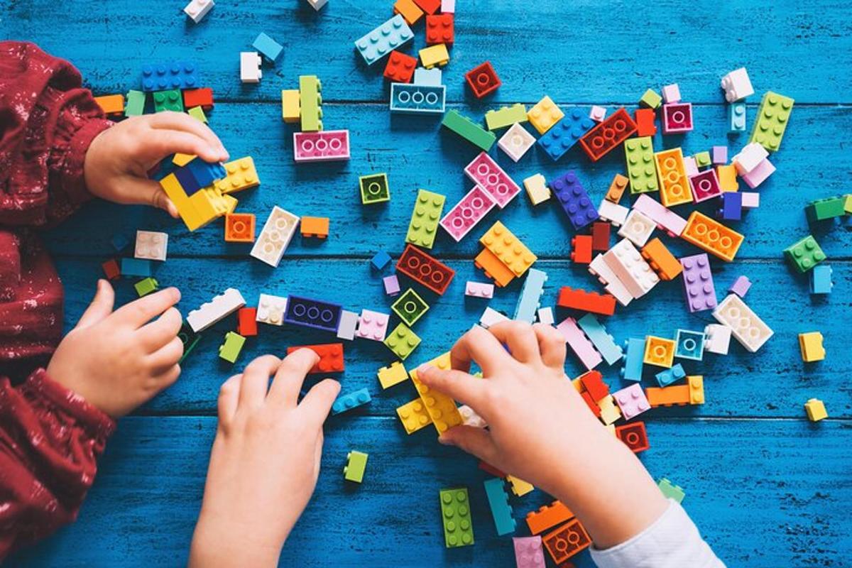 due bambini che giocano con i mattoncini Lego su un tavolo blu
