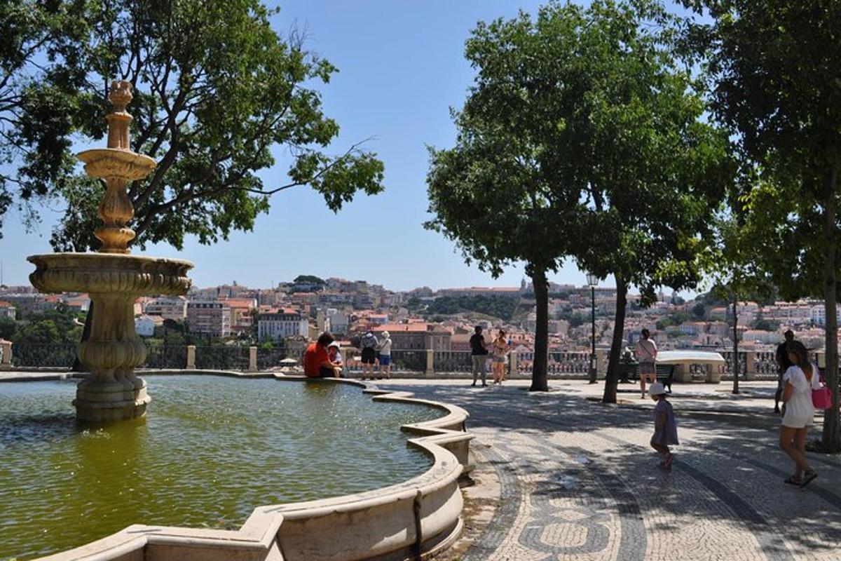 ein Brunnen in einem Park, um den herum Menschen spazieren gehen