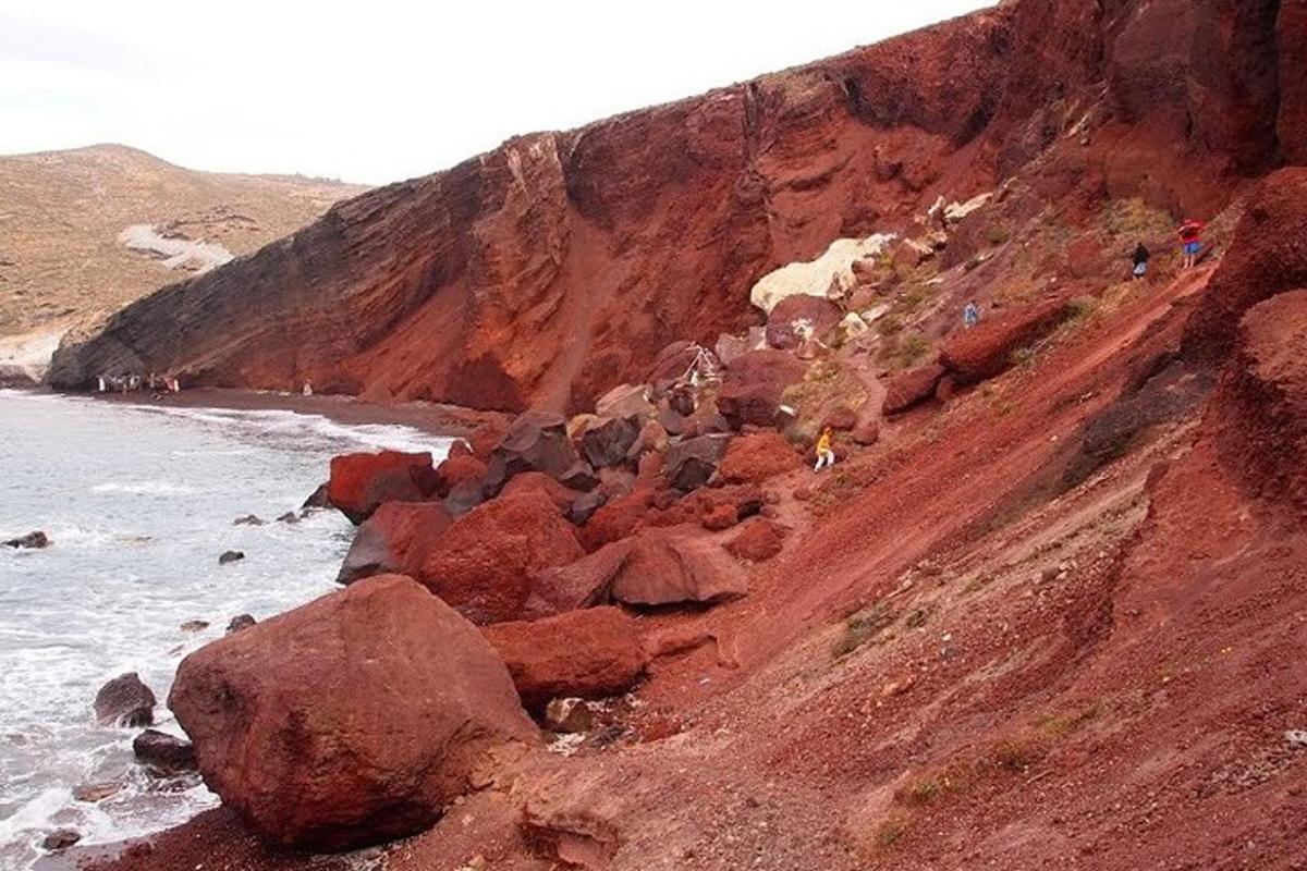 a group of people walking on a rocky hill next to the ocean