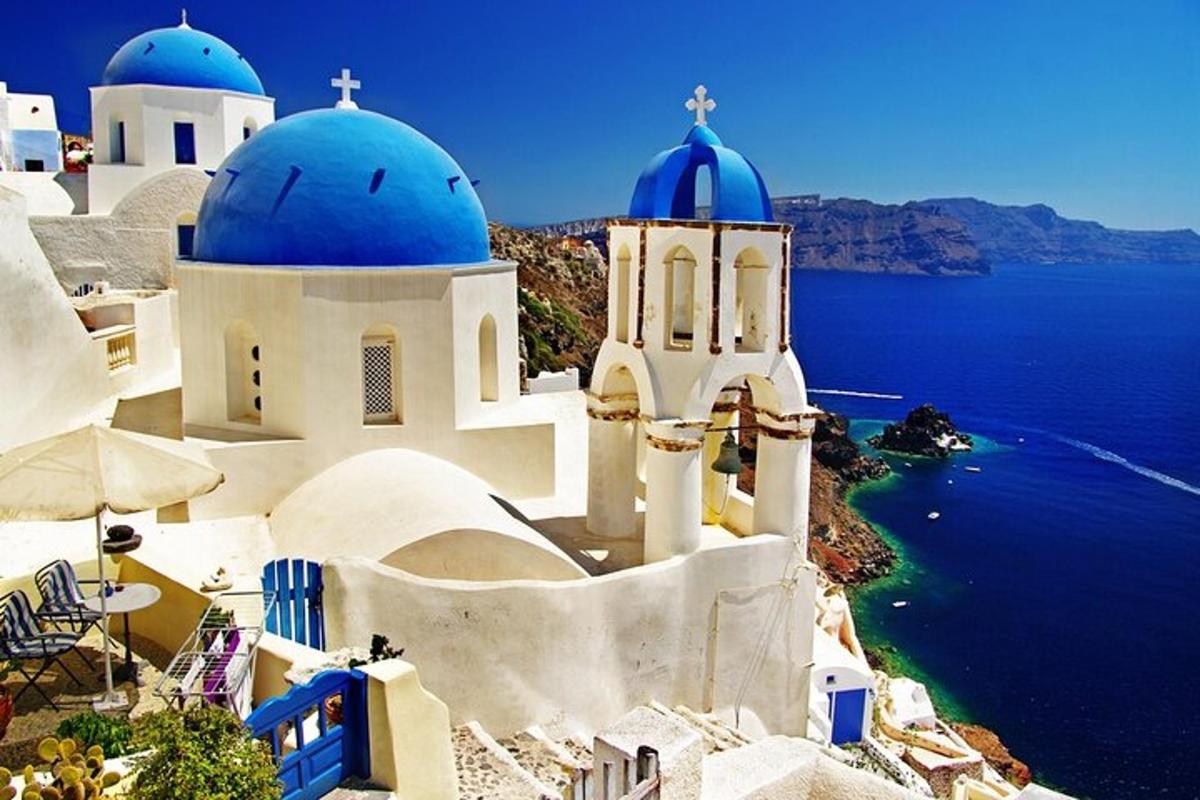 μια ομάδα λευκών κτιρίων με μπλε θόλους και τον ωκεανό