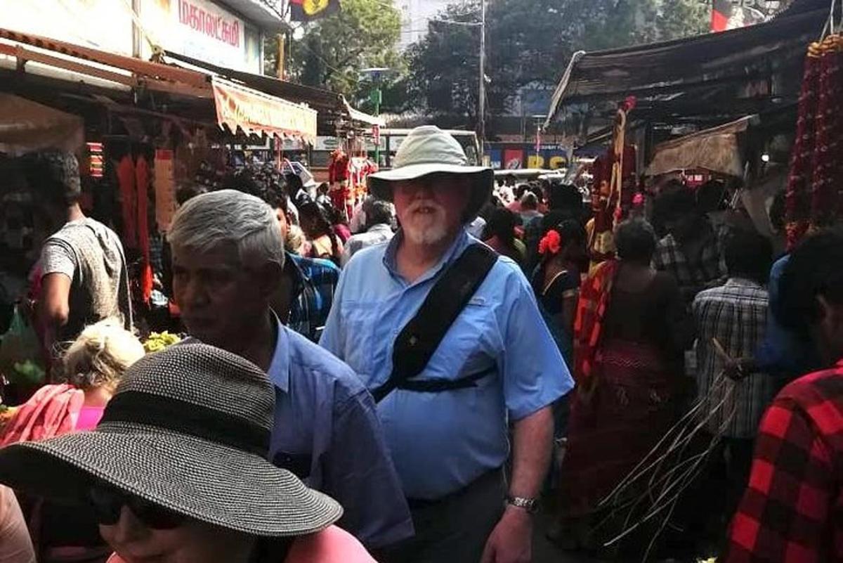 a man in a hat walking through a crowded market