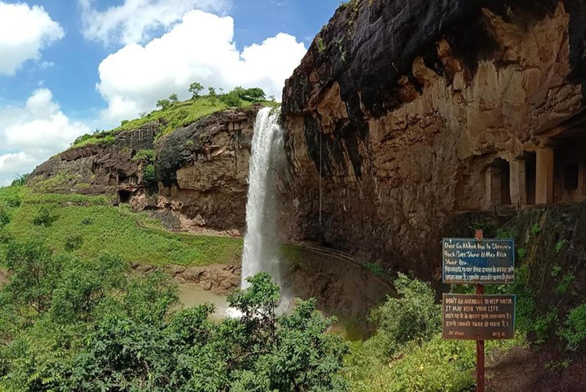a waterfall on the side of a mountain with a sign