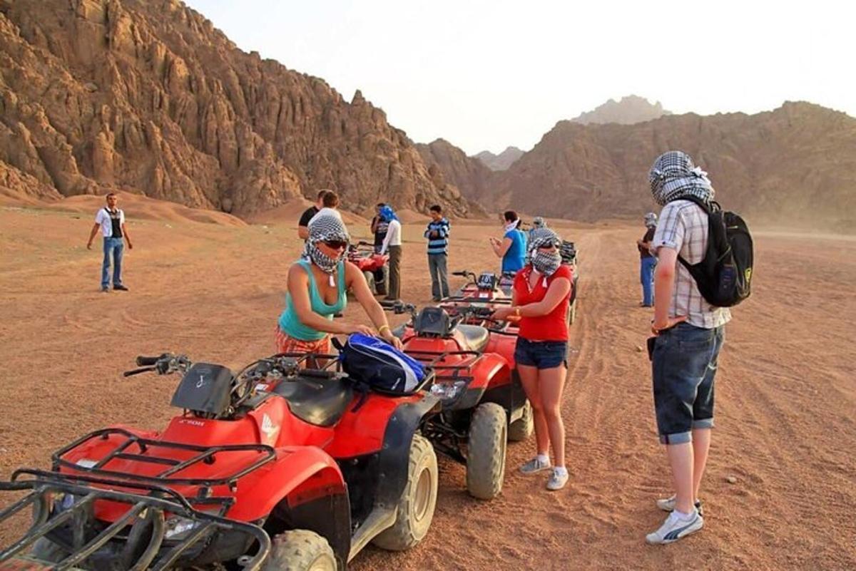 a group of people standing around atvs in the desert