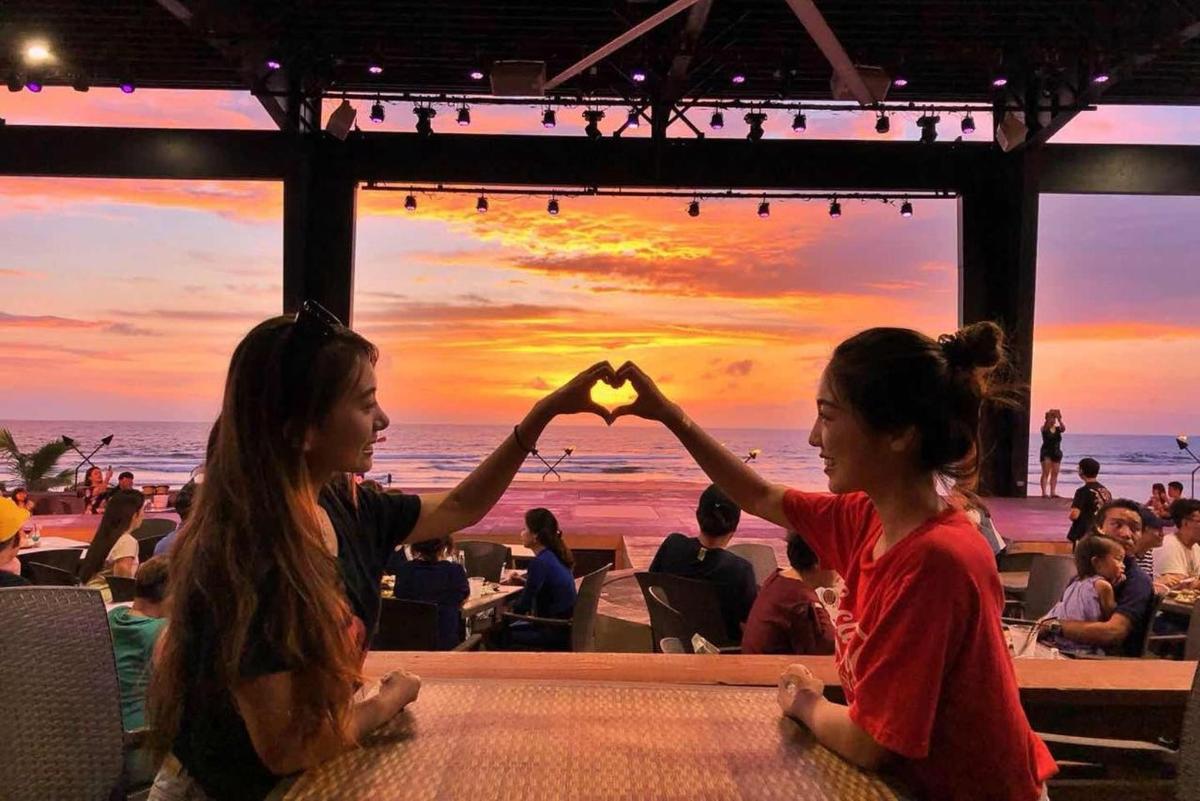 two girls sitting at a table making a heart with their hands