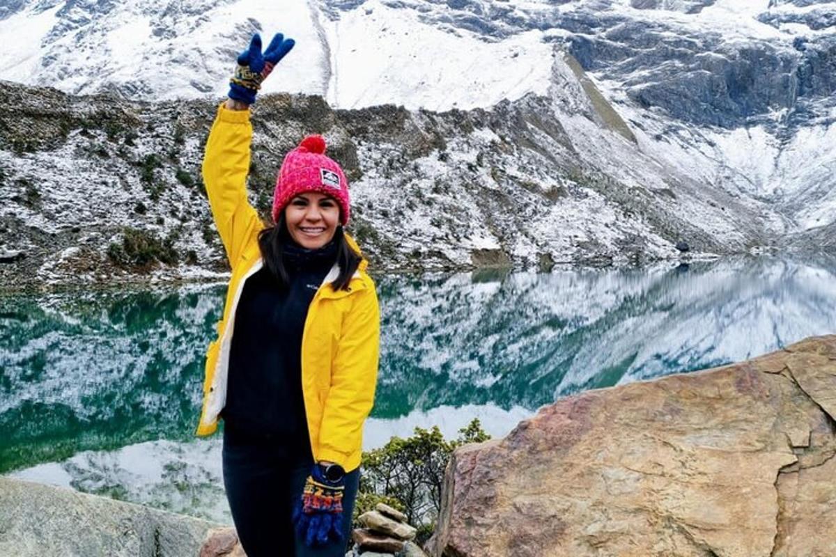 uma mulher em pé no topo de uma montanha com a mão no ar