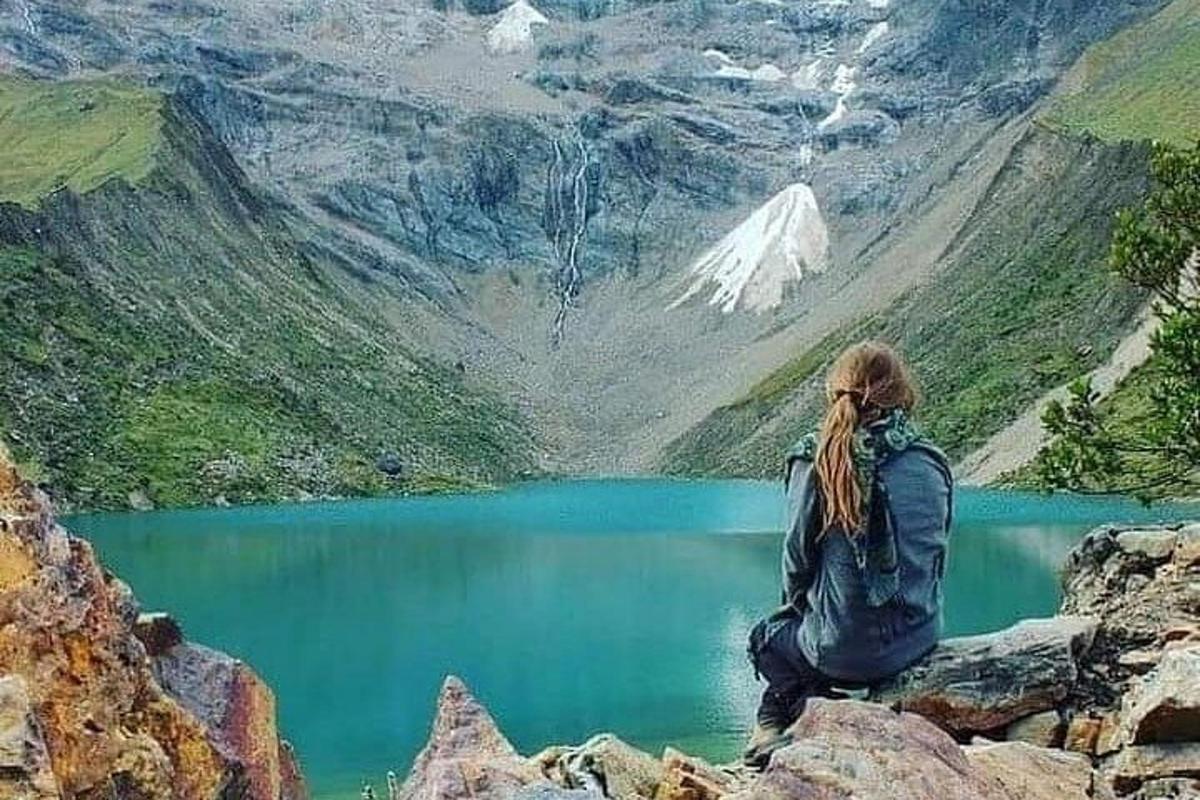 uma mulher sentada em uma rocha com vista para um lago na montanha