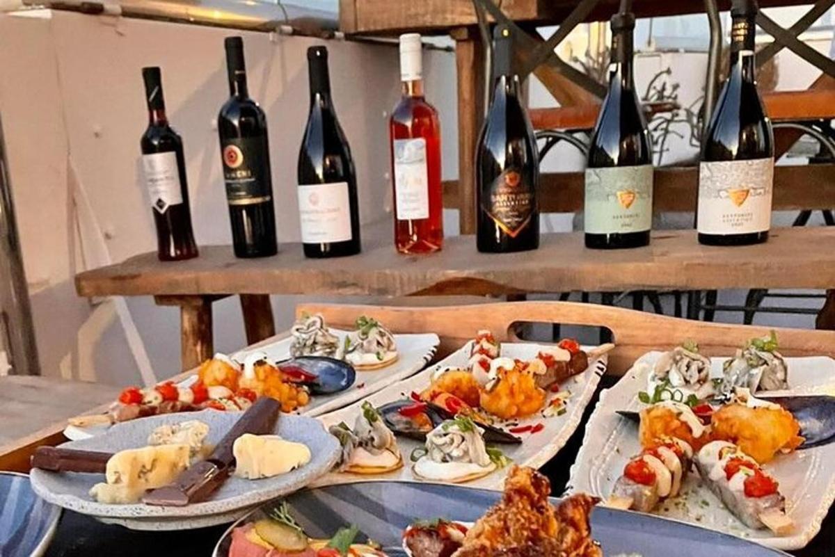 un tavolo con tre piatti di cibo e bottiglie di vino