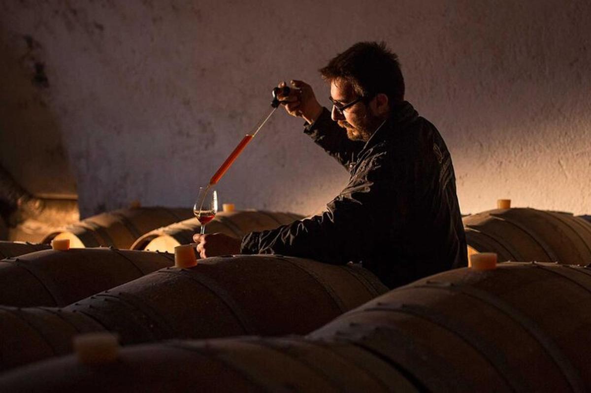 un uomo che tiene in mano una bottiglia e un bicchiere di vino