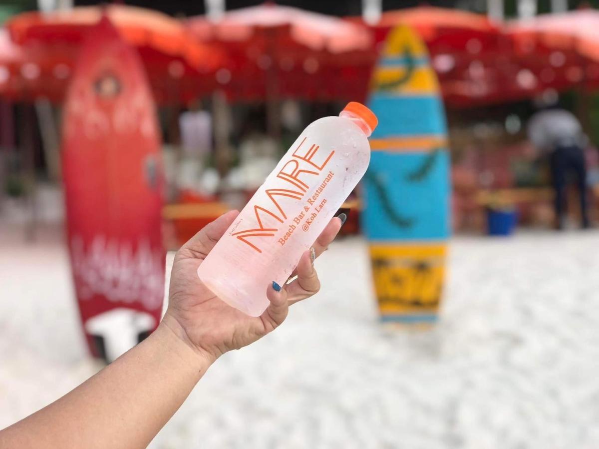 a hand holding a water bottle in front of a playground