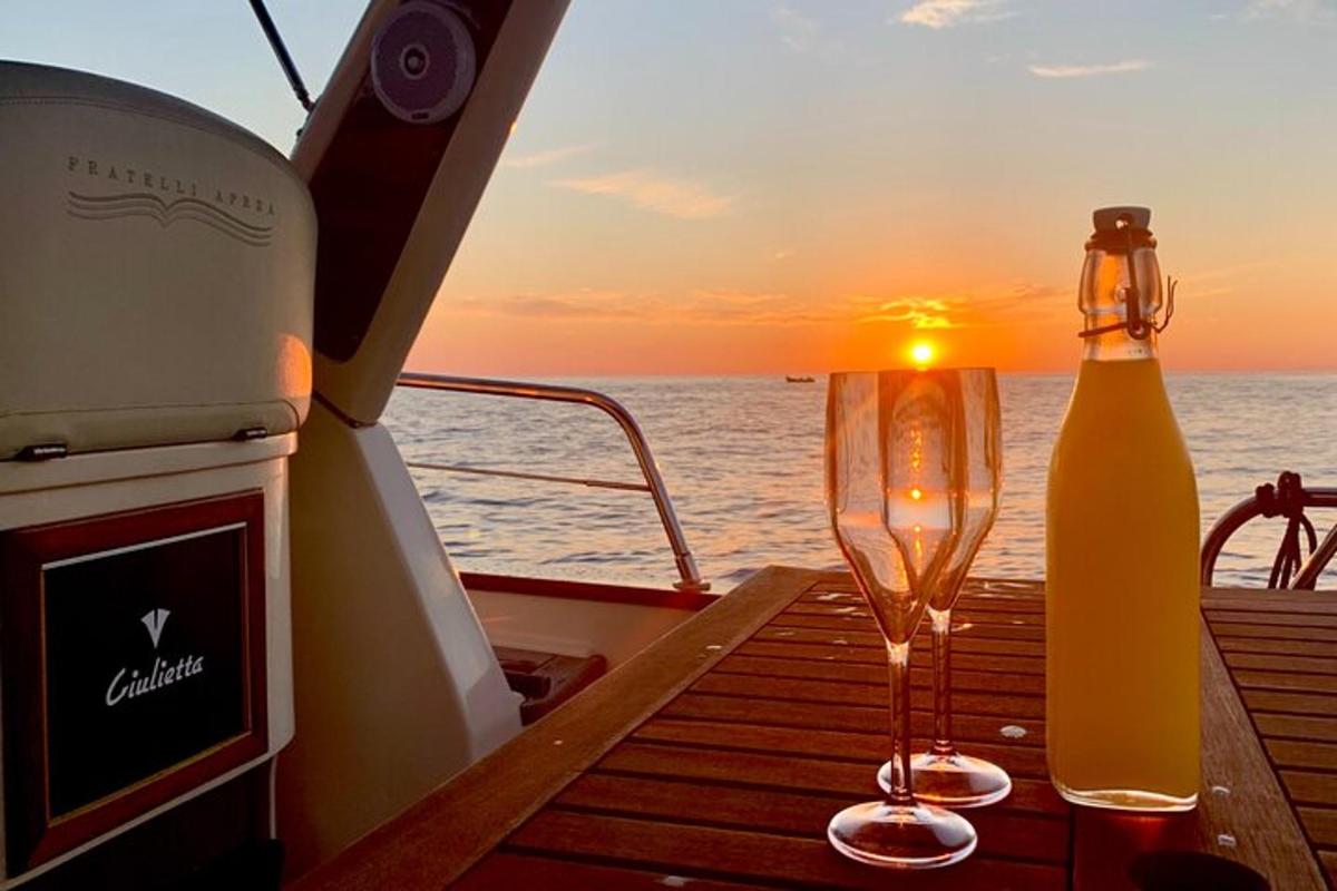 a wine glass and a bottle on a boat with the sunset