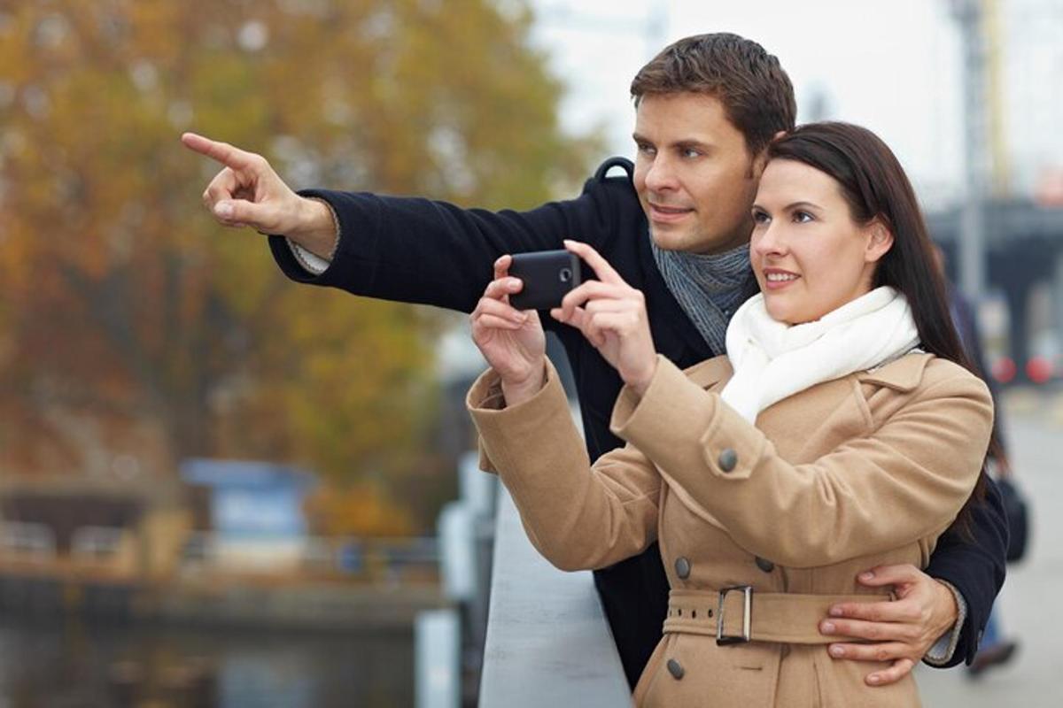 muž fotí ženu mobilním telefonem