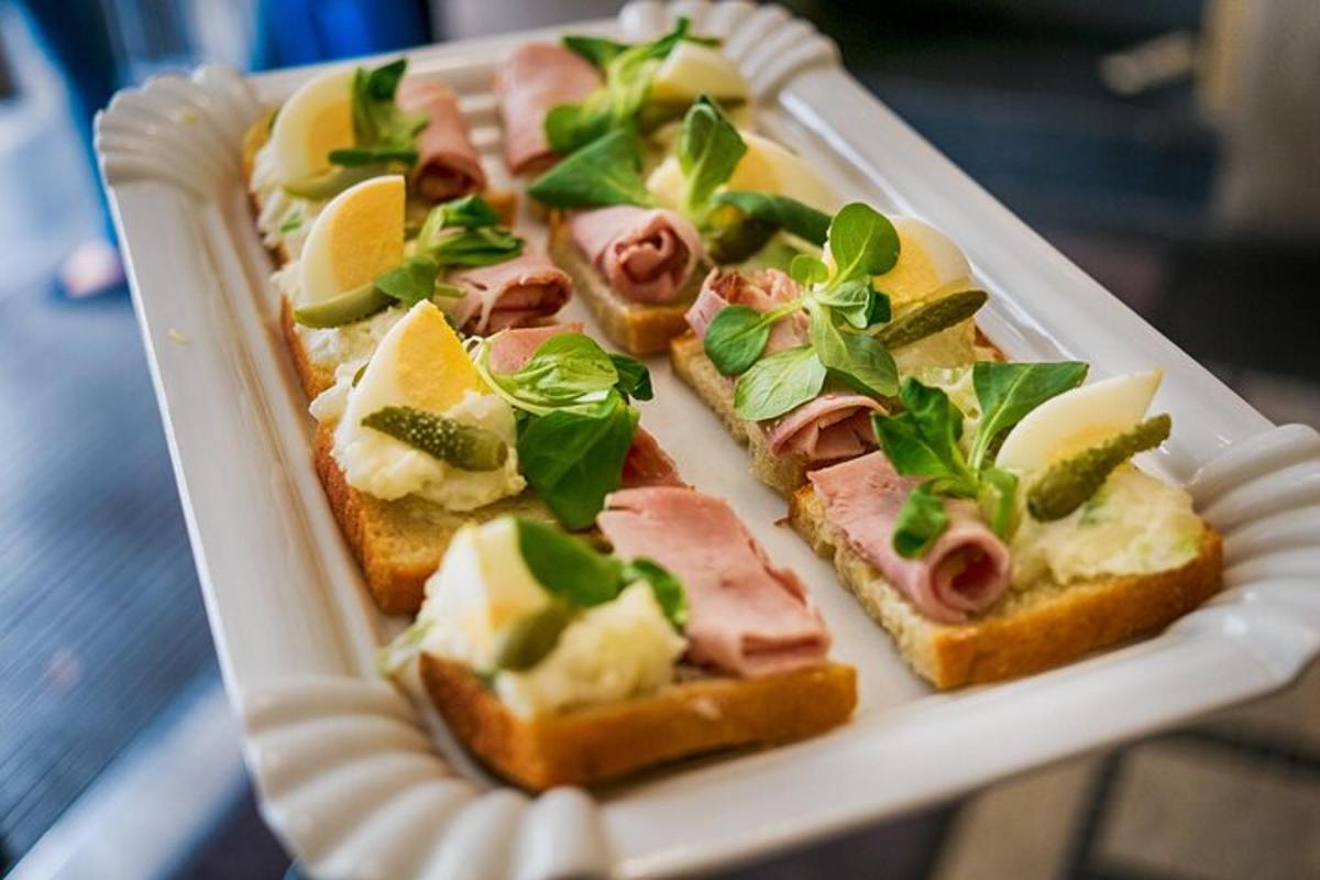 en hvit tallerken toppet med brødskiver med skinke og grønnsaker