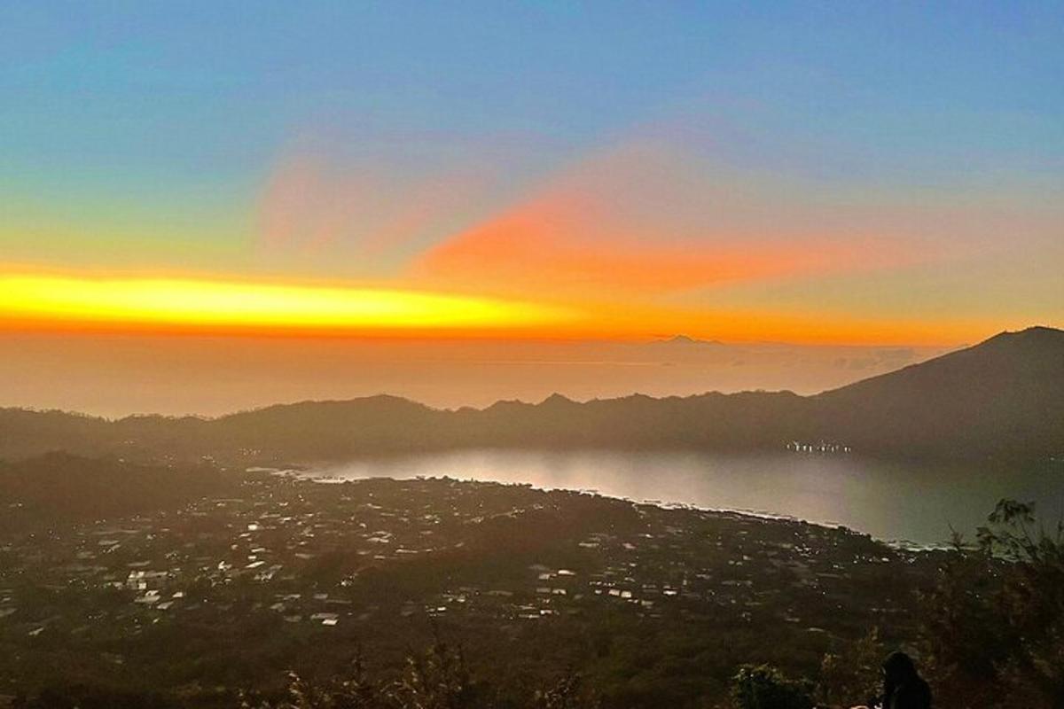 seseorang yang berdiri di atas bukit melihat matahari terbenam