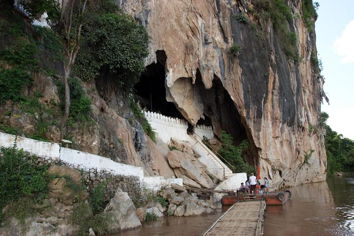 a cave in the side of a mountain with people on a boat
