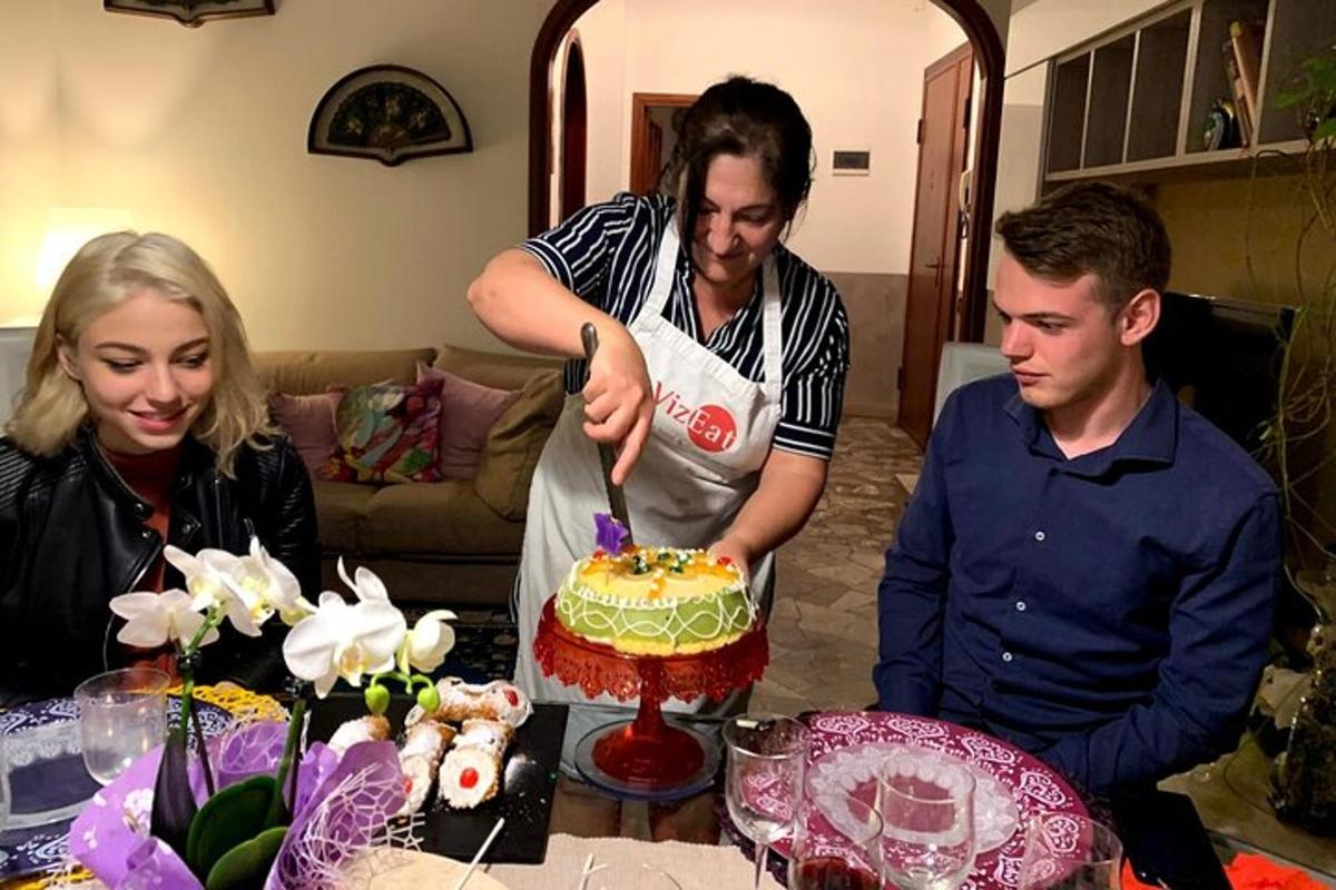 skupina lidí stojících kolem stolu a krájejících dort