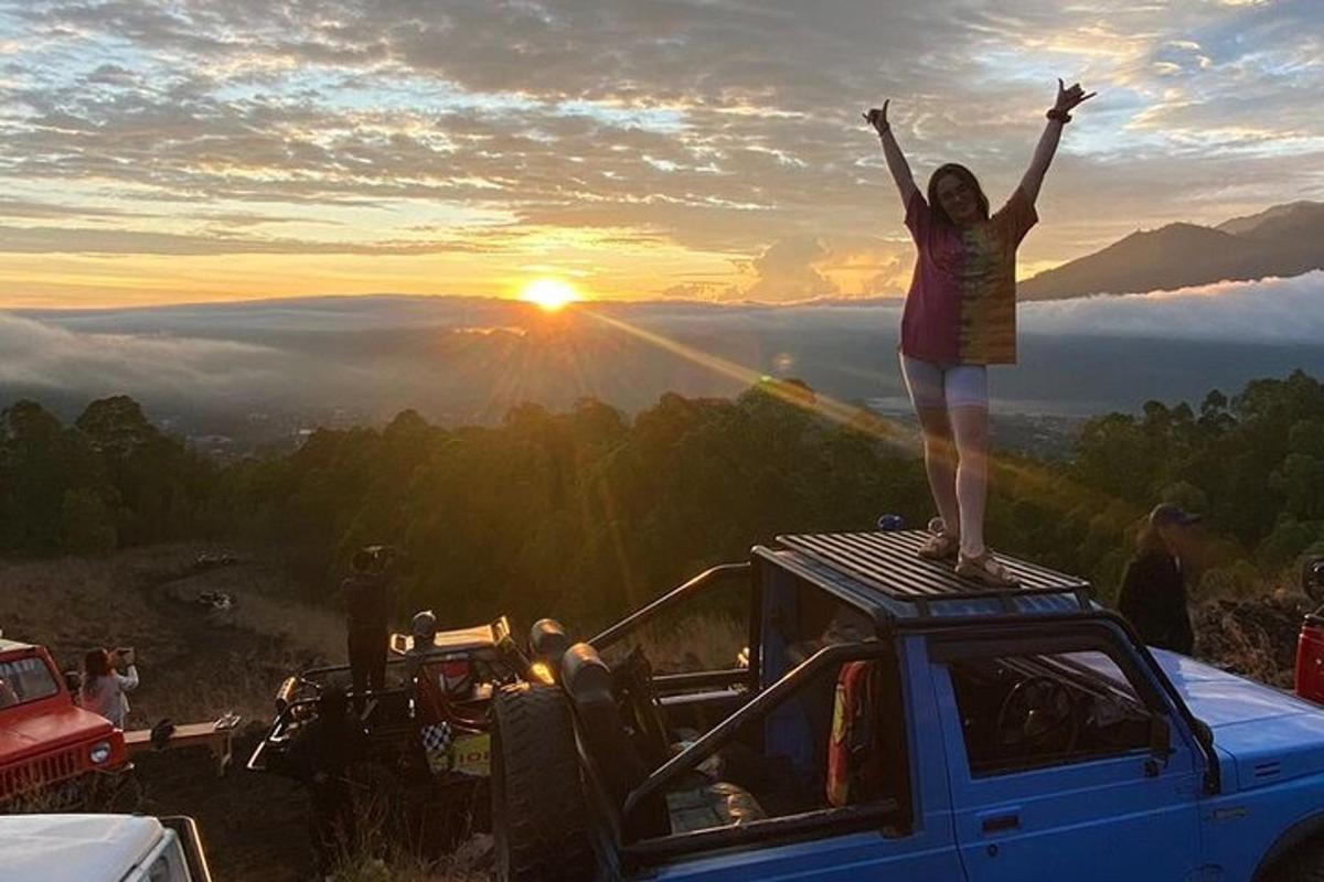 a woman standing on top of a car with her arms in the air