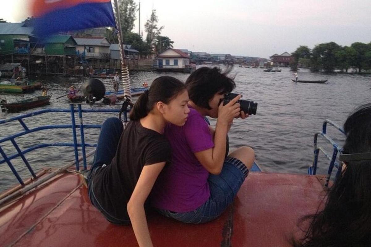 Bir teknede oturup fotoğraf çeken iki kişi