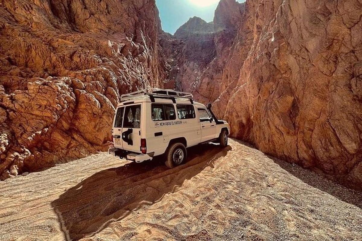 một chiếc xe jeep màu trắng đang chạy trên con đường đất trong hẻm núi