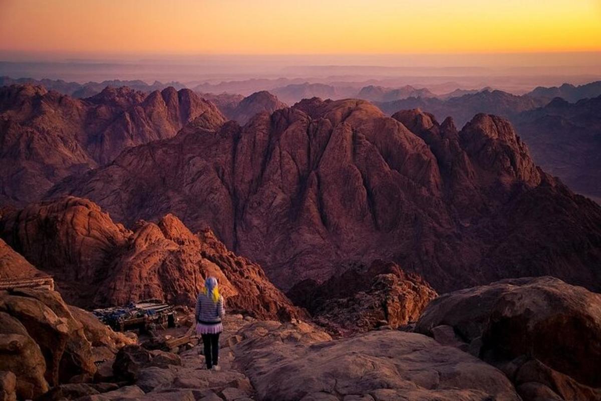 una persona parada en la cima de una montaña al atardecer