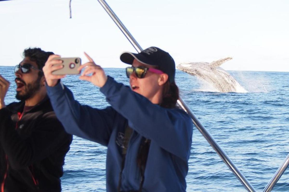 a woman taking a picture of a fish on a boat