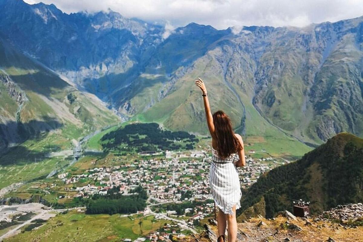 una donna in piedi sulla cima di una montagna con la mano alzata in aria