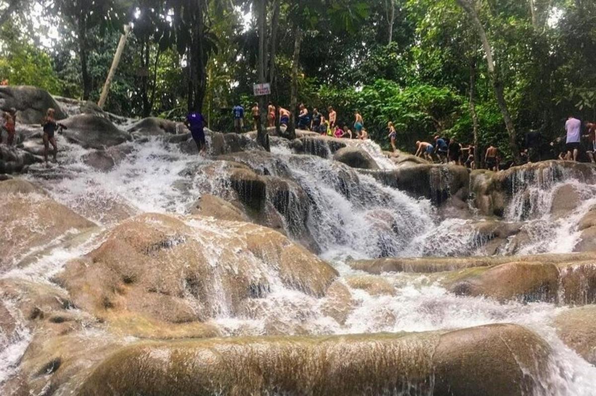 um grupo de pessoas em pé sobre as rochas de uma cachoeira