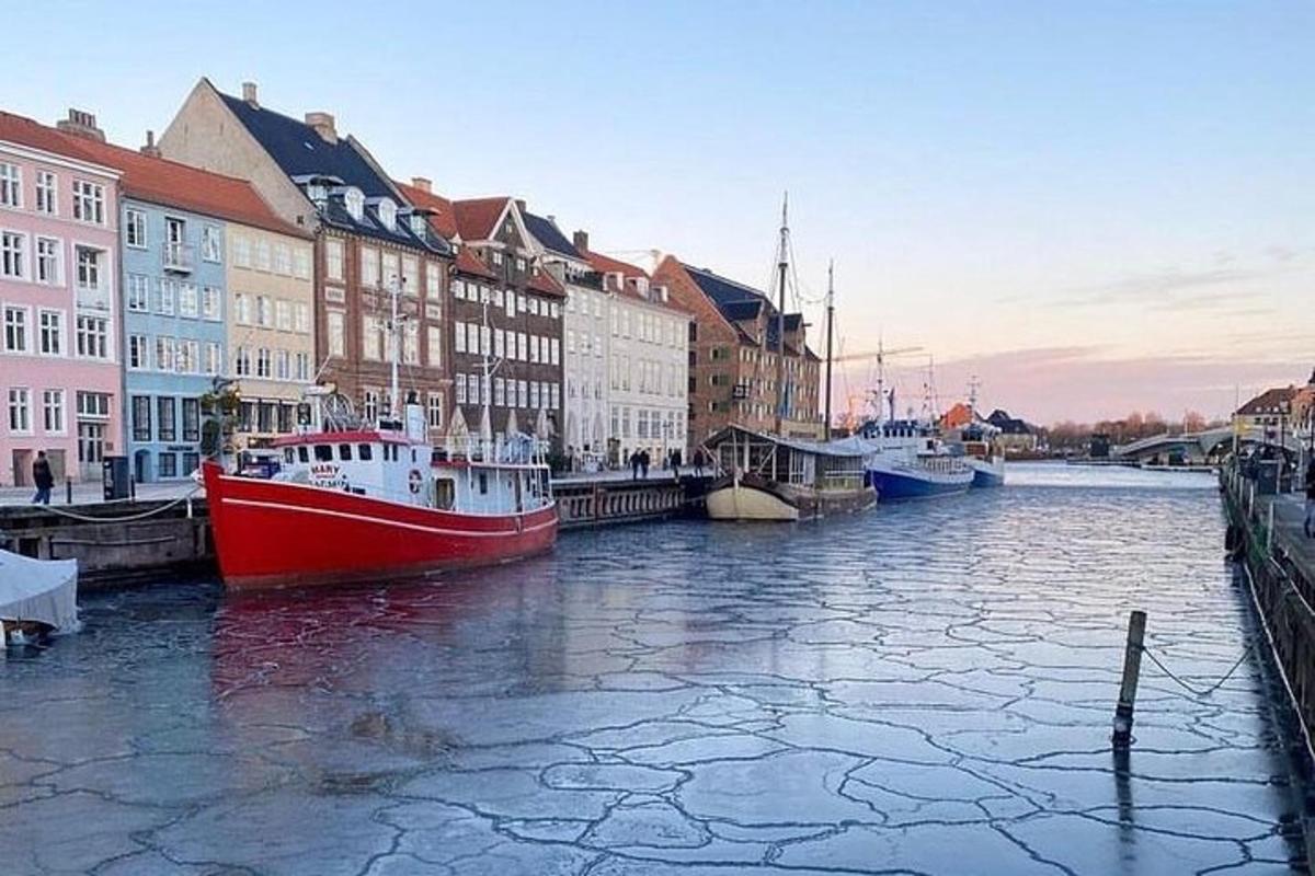 en rød og hvit båt i en elv med bygninger