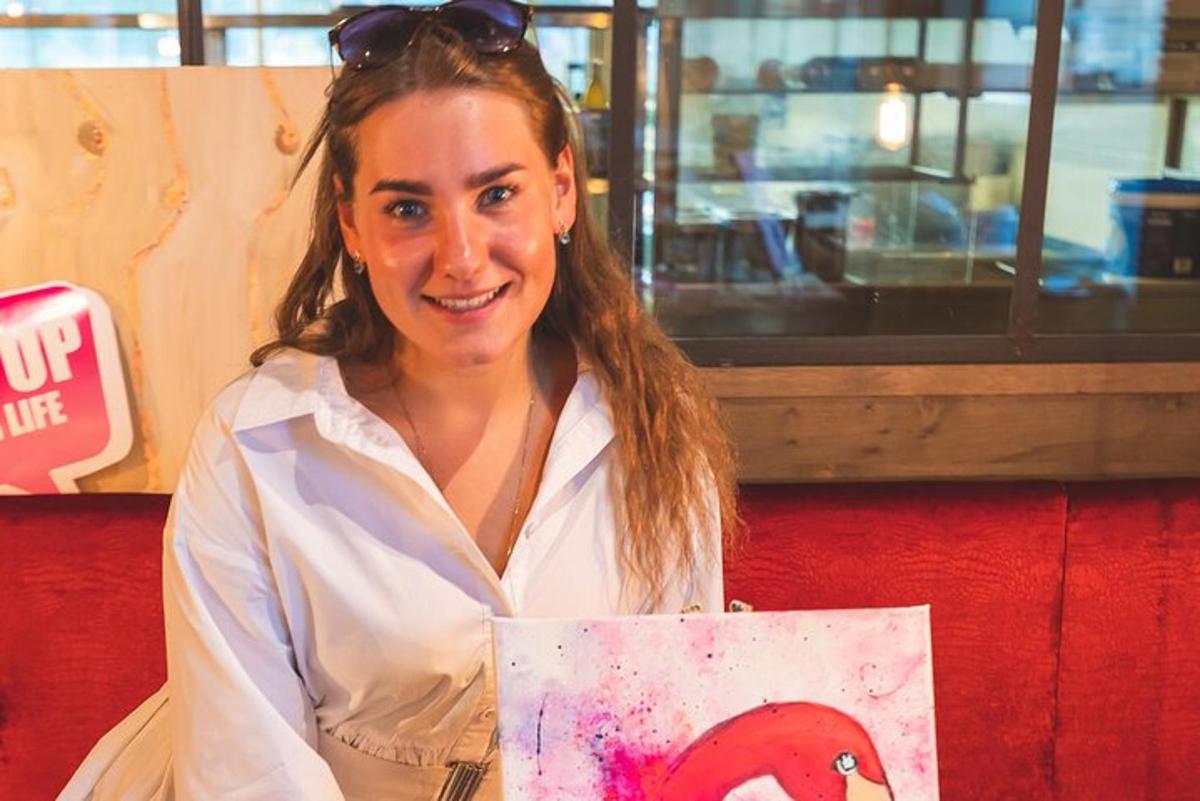 Una mujer sosteniendo un cuadro de un pollo rojo.