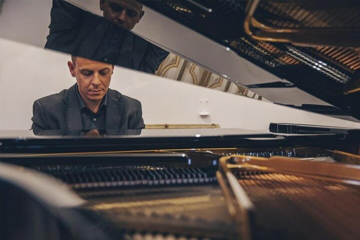 a man sitting at a piano with an umbrella