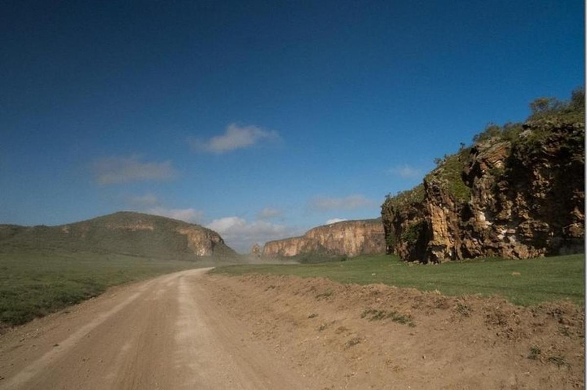 uma estrada de terra no meio de um campo com montanhas