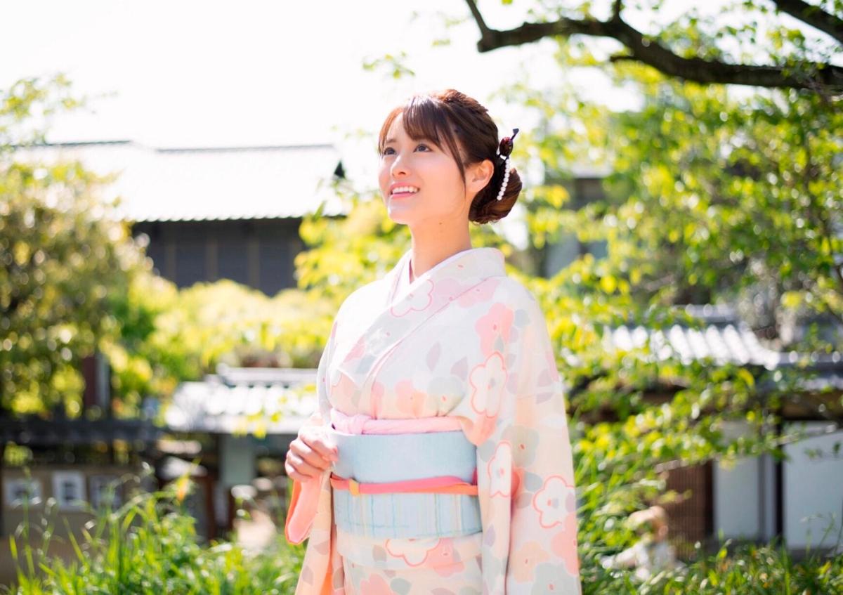 a woman wearing a kimono standing in a park