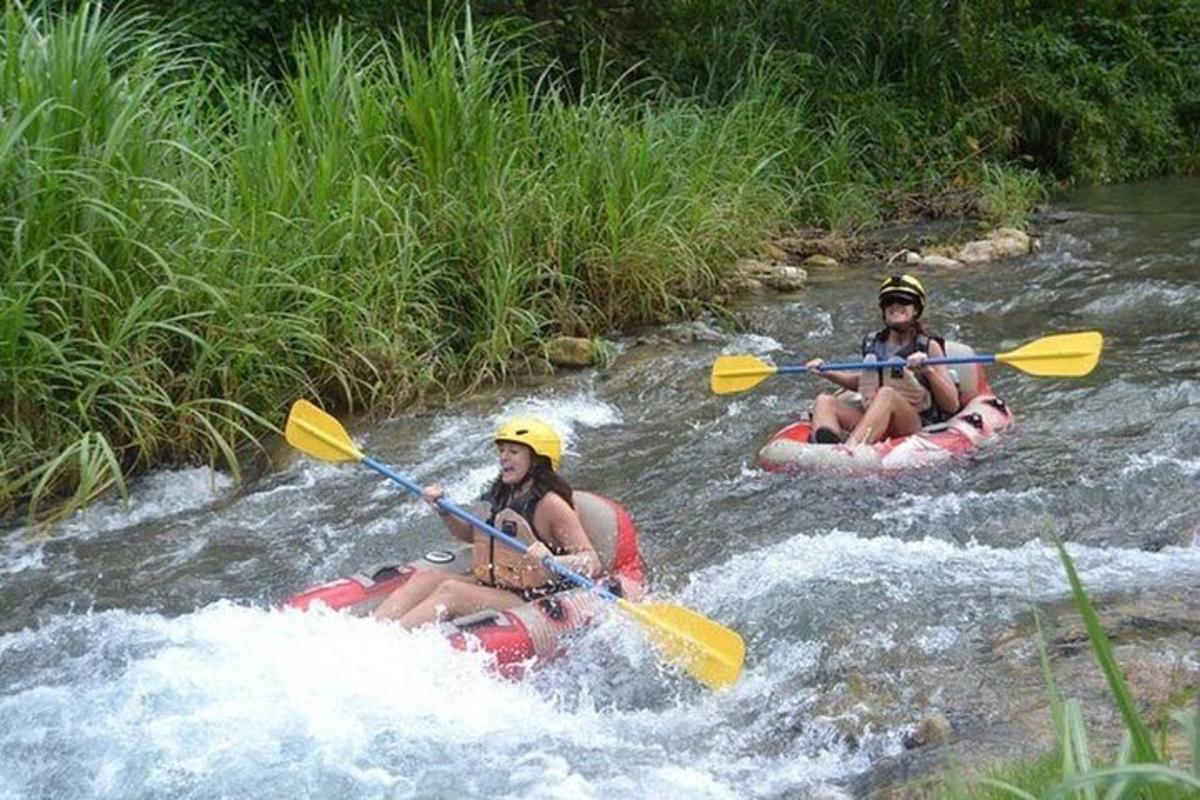 dua orang sedang berakit menyusuri sungai di jeram
