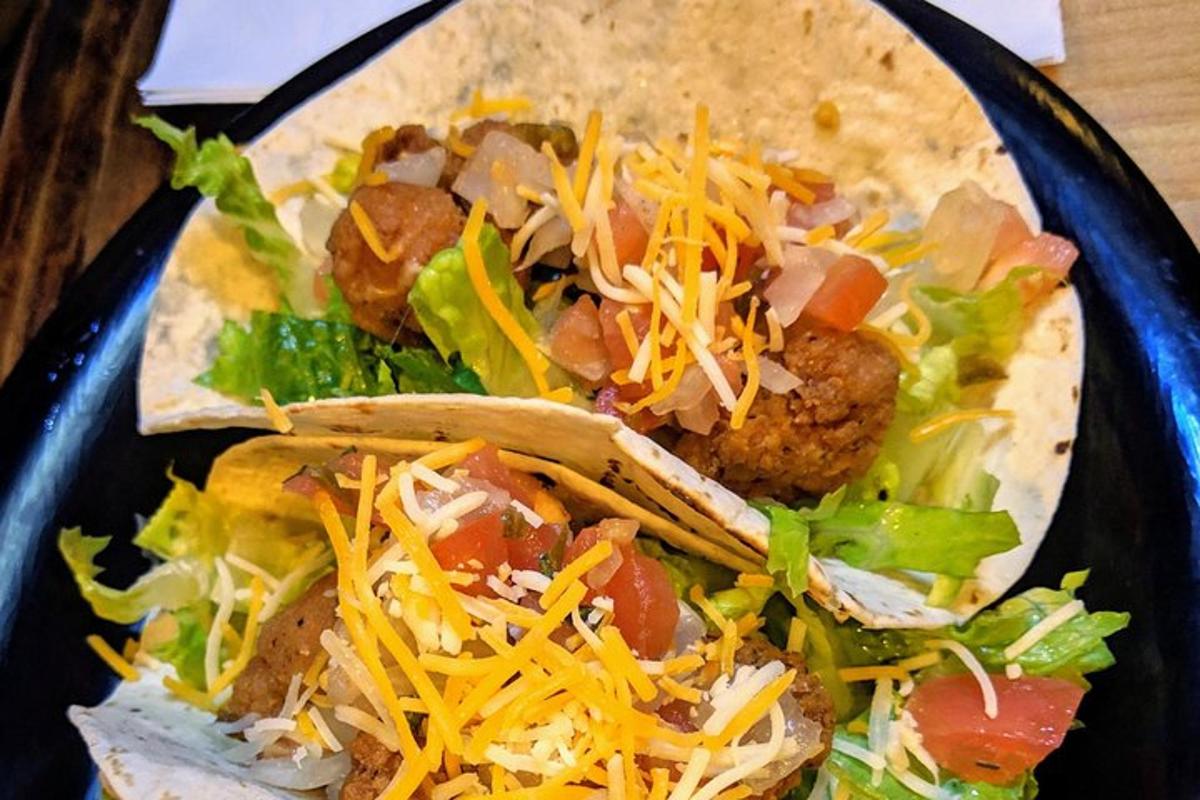 a black plate of food with tacos and cheese
