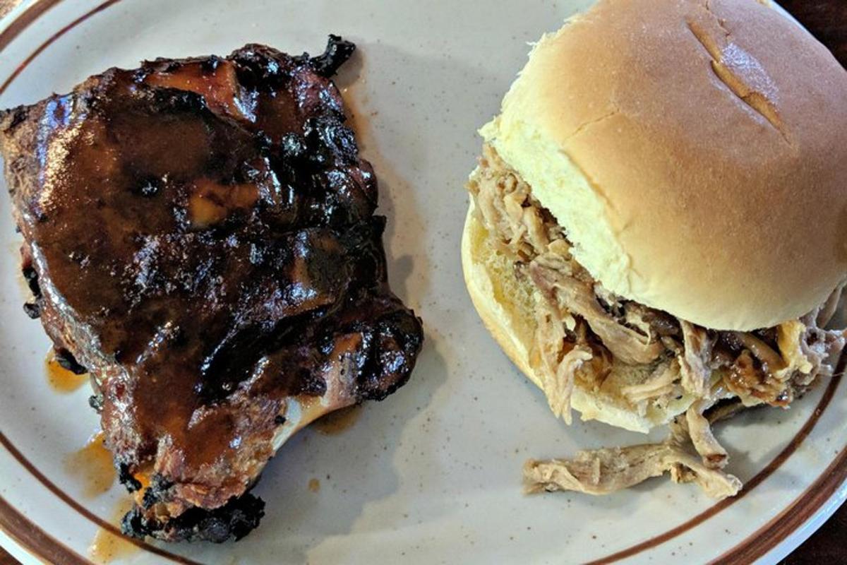a pulled pork sandwich on a white plate next to a sandwich