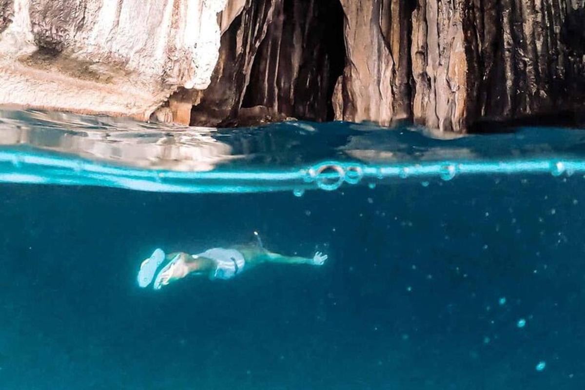 a person swimming in the water near a cliff
