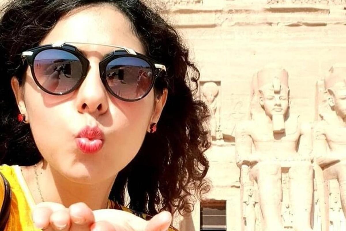 a woman sticking her tongue out in front of a statue