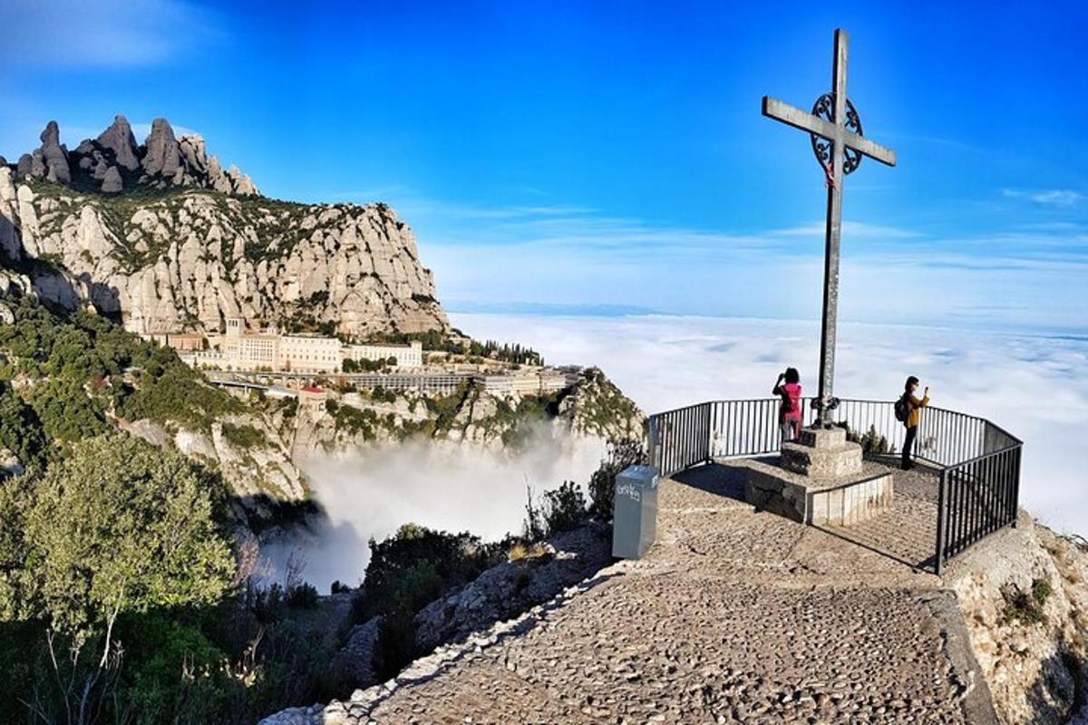 Una cruz en el borde de una montaña con gente de pie sobre ella.